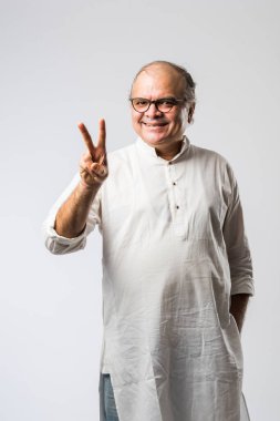 Mutlu Hintli emekli bir adamın portresi beyaz kurta giyer, işaret eder, sunar ya da katlanmış poz verir.