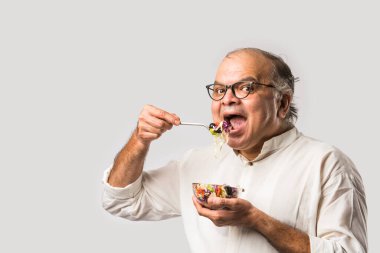 Kıdemli Hintli adam taze yeşil salata yiyor. Olgun erkek sağlıklı beslenme, sağlık, beslenme konsepti
