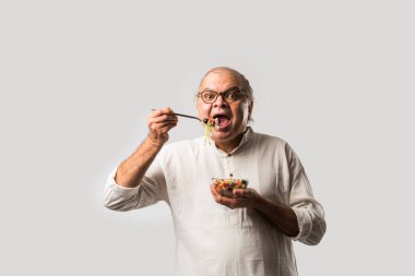 Kıdemli Hintli adam taze yeşil salata yiyor. Olgun erkek sağlıklı beslenme, sağlık, beslenme konsepti