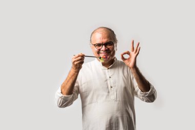 Kıdemli Hintli adam taze yeşil salata yiyor. Olgun erkek sağlıklı beslenme, sağlık, beslenme konsepti