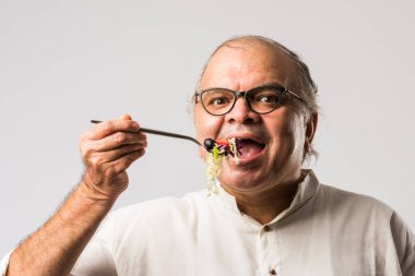 Kıdemli Hintli adam taze yeşil salata yiyor. Olgun erkek sağlıklı beslenme, sağlık, beslenme konsepti