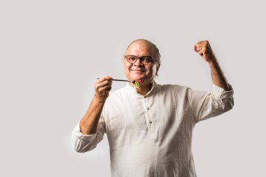 Kıdemli Hintli adam taze yeşil salata yiyor. Olgun erkek sağlıklı beslenme, sağlık, beslenme konsepti