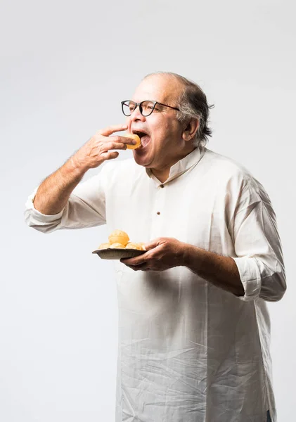 Indian old man eating panipuri, phuchka, gupchup or golgappa