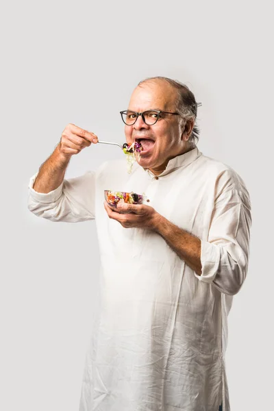 stock image Senior Indian asian man eating fresh green salad. Mature male male having healthy snack, healthcare, diet concept