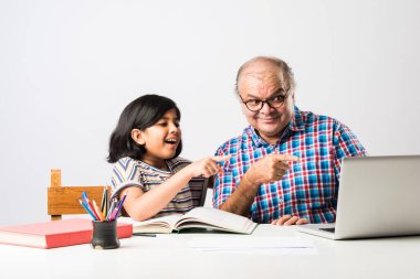 Hintli büyükbaba torununa kitap, kalem ve dizüstü bilgisayar, evde eğitim ya da eğitim öğretiyor.