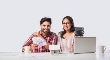 Odaklanmış Hintli genç çift muhasebe, fatura hesaplama, online bankacılık hizmetleri ve hesap makinesi kullanarak birlikte bütçe planlama tartışması, mali durumları kontrol