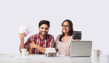 Odaklanmış Hintli genç çift muhasebe, fatura hesaplama, online bankacılık hizmetleri ve hesap makinesi kullanarak birlikte bütçe planlama tartışması, mali durumları kontrol