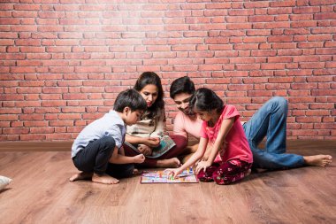 Dört kişilik Hintli genç aile karantinada Satranç, Ludo veya Atıştırmalık ve Merdiven gibi masa oyunları oynuyor.