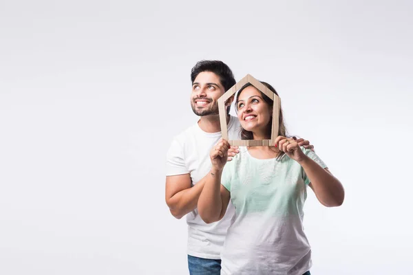 Indian young family couple and real estate concept - buying or rental, standing against white background