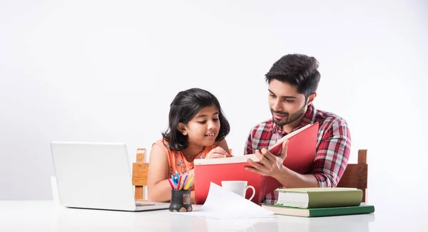 Cute Indian girl with father studying or doing homework at home using laptop and books - online schooling concept