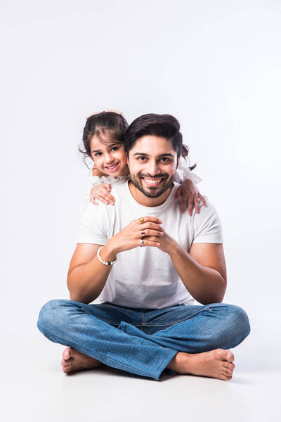 Любящий индийский папочка обнимает милую маленькую очаровательную дочь, сидящую на коленях или на спине - концепция, показывающая любовь, заботу, близкого человека, день отца