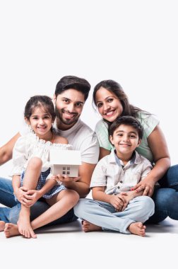 Hintli aile babası, anne, oğul ve kız ellerinde ev modelleri tutuyorlar - Hindistan 'da emlak kavramı