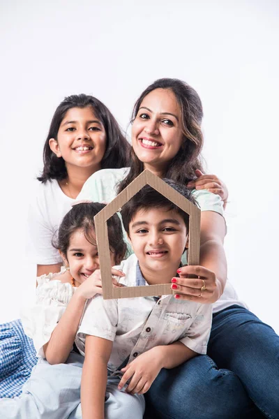 Indian family Father, mother, son and daughter holding 3D paper model of home - Real Istate Concept in India