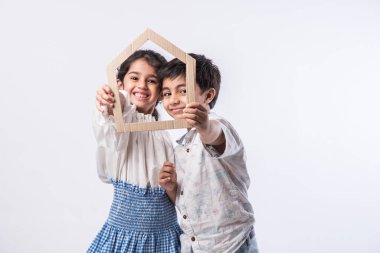 Hintli çocuklar ellerinde 3 boyutlu kağıt ev modeli tutuyorlar - el işi ya da gayrimenkul kavramı gösteriyorlar