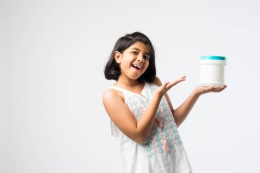 Beyaz arka planda dururken plastik şişe sunan Hintli küçük kız.