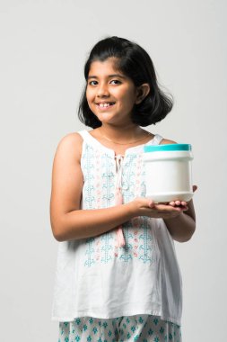 Beyaz arka planda dururken plastik şişe sunan Hintli küçük kız.