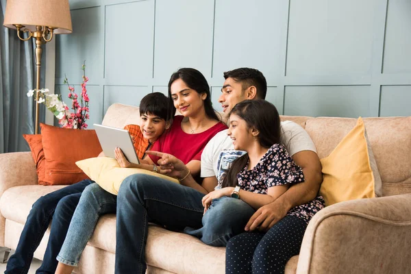 Indian Family Sitting Sofa Using Smartphone Laptop Tablet Watching Movie — Stock Photo, Image