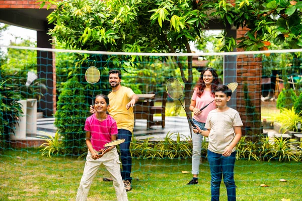 Hindistan 'ın küçük erkek kardeşi açık alanda badminton oynuyor, Asyalı küçük kardeşler gündüz vakti mekik ve raketle eğleniyor, aktif çocukluk anı.