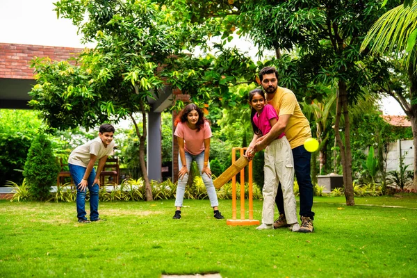 Ev bahçesinde kriket oynayan Hintli bir aile, açık hava sporları oynayarak kaliteli zaman geçiriyor, neşeli Asyalı ebeveynler ve çocuklar güneşli bir günde arka bahçedeki aktivitelerin keyfini çıkarıyorlar.