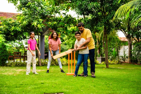 200 karakterli Hintli aile ev bahçesinde kriket oynuyor, açık hava sporları oynayarak kaliteli zaman geçiriyor, neşeli Asyalı ebeveynler ve çocuklar güneşli bir günde arka bahçedeki aktivitelerin keyfini çıkarıyorlar.
