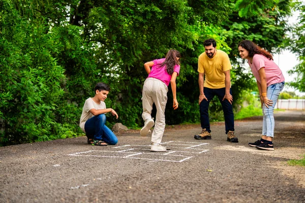 Ev bahçesinde geleneksel bir seksek oyunu olan Tikkar Billa ailesi, çocuklarla meydanda zıplayarak ve nostaljik açık hava sporlarının keyfini çıkararak kaliteli zaman geçiriyor.