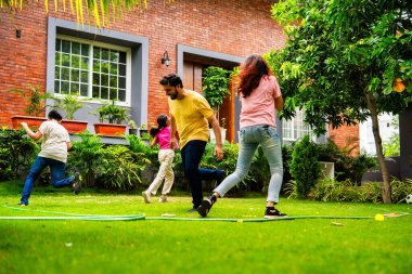 Ev bahçesinde Langdi oyunu oynayan Hintli bir aile, açık hava sporlarından zevk alarak birlikte kaliteli zaman geçiriyorlar, geleneksel Hint takım oyununda tek ayak üzerinde zıplayıp çeviklik tabanlı oyunu birleştiriyorlar.