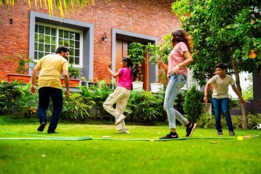 Ev bahçesinde Langdi oyunu oynayan Hintli bir aile, açık hava sporlarından zevk alarak birlikte kaliteli zaman geçiriyorlar, geleneksel Hint takım oyununda tek ayak üzerinde zıplayıp çeviklik tabanlı oyunu birleştiriyorlar.