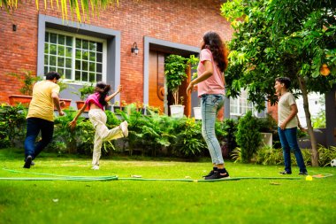 Ev bahçesinde Langdi oyunu oynayan Hintli bir aile, açık hava sporlarından zevk alarak birlikte kaliteli zaman geçiriyorlar, geleneksel Hint takım oyununda tek ayak üzerinde zıplayıp çeviklik tabanlı oyunu birleştiriyorlar.