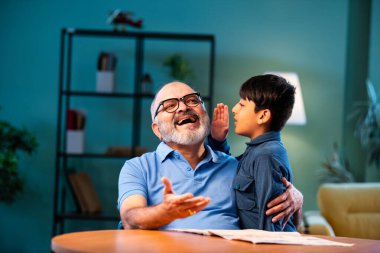 Hintli çocuk, büyükbabasına evde dedikodu yapıyor. Büyükbabası masada otururken sırrını paylaşıyor. Çocuk, evde yaşlı bir adama gizli haberler fısıldıyor.
