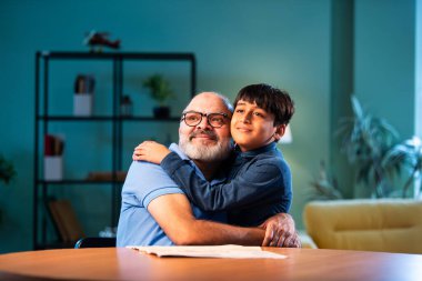 Hintli çocuk büyükbabaya evde sarılıyor. Büyükbaba masada otururken sevgi ve şefkat gösteriyor. Evde yaşlı bir adamla aile bağı kuruyor.