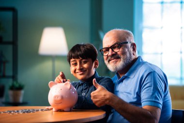 Hintli büyükbaba çocuklara evde kumbarada para biriktirmeyi öğretiyor, yaşlı adam torununa mali disiplin konusunda rehberlik ediyor, iyi para alışkanlığını güvence altına alıyor, aile bağlarını güvence altına alıyor.