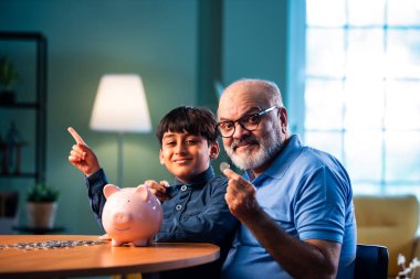 Hintli büyükbaba çocuklara evde kumbarada para biriktirmeyi öğretiyor, yaşlı adam torununa mali disiplin konusunda rehberlik ediyor, iyi para alışkanlığını güvence altına alıyor, aile bağlarını güvence altına alıyor.