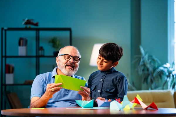 Hintli büyükbaba ve çocuk evde kağıt işleriyle uğraşıyorlar, renkli tekne ve uçakları parlak kağıtlarla eğitiyorlar, yaşlı adam torununa yaratıcı aktiviteler öğretiyor, aile içi bağlar kuruyor.