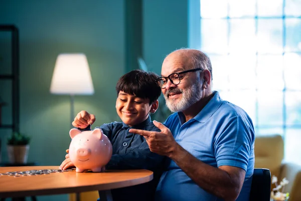 Hintli büyükbaba çocuklara evde kumbarada para biriktirmeyi öğretiyor, yaşlı adam torununa mali disiplin konusunda rehberlik ediyor, iyi para alışkanlığını güvence altına alıyor, aile bağlarını güvence altına alıyor.