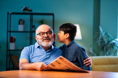 Hintli çocuk, büyükbabasına evde dedikodu yapıyor. Büyükbabası masada otururken sırrını paylaşıyor. Çocuk, evde yaşlı bir adama gizli haberler fısıldıyor.