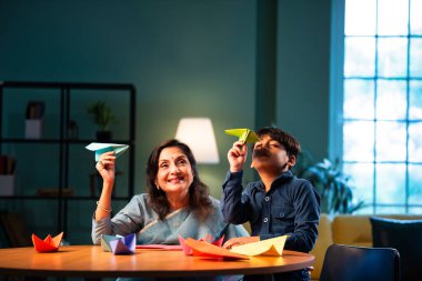 Hintli büyükanne, modern evlerde çocukların masada kağıt uçak yapmasına yardım ediyor. Yaşlı kadın, torununa yaratıcı kağıt işlerinde rehberlik ediyor. Aile bağları, mutlu mesut iki insanı birbirine bağlıyor.