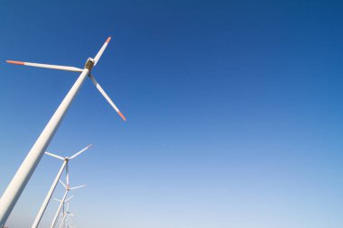 yatay satır beyaz rüzgârdan rüzgar türbinleri enerji kümesindeki boşaltmak ile açık mavi gökyüzü karşı ön görünüm açılı