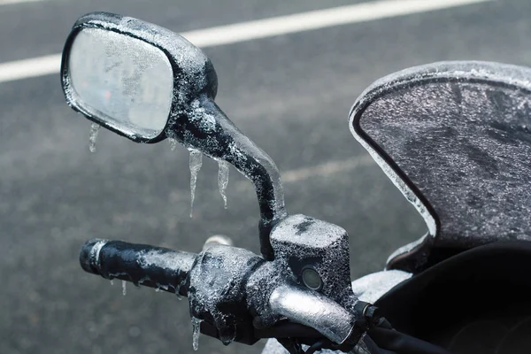 摩托车冷冻挡风玻璃车把和后视镜的后视镜特写镜头覆盖在冰柱在冬季与城市街道在前景 — 图库照片
