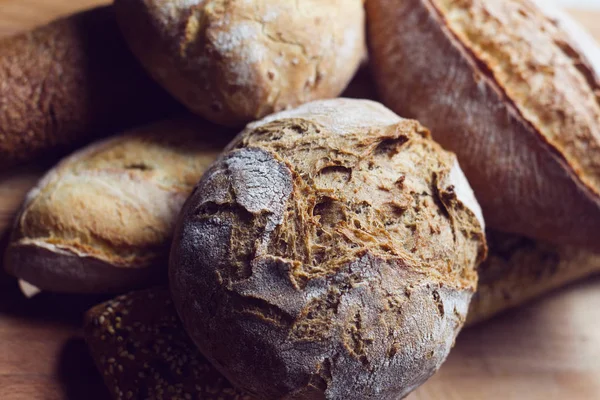 Diferentes tipos de pan en la tabla de cortar cocina de madera — Foto de Stock