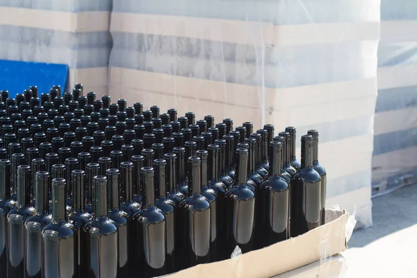 black wine bottles on pallets in outside storage area