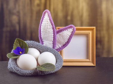 Menekşe, Paskalya için tasarım arka planı kavramı çiçeklerin örme çanta ahşap bir arka plan üzerinde renkli tavuk yumurtası yalan