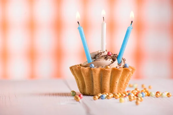 Appetizing cupcake with three candles on a retro background