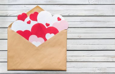 Zarf gri vintage ahşap arka plan üzerinde pembe, kırmızı veya beyaz kağıt yürekleri.