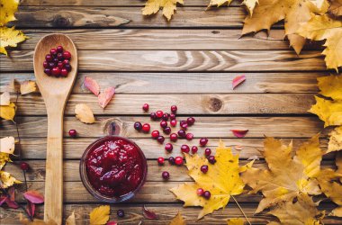 Kızılcık ve sonbahar yaprakları üzerinde ahşap arka plan. Kızılcık reçeli. Sonbahar vitaminler.