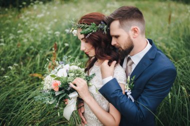 Arkasında, şefkatle kucaklayan gelin damat. Gelin gerçek çiçek çelenk ile.