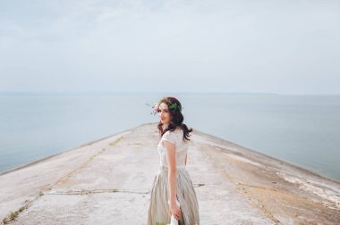 Çelenk ve buket nehir arka planı ayakta elinde gelinle.