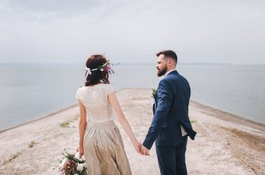 Arkadan Görünüş elele, birbirine bakarak yan yana yürümeye yeni evli çiftin.