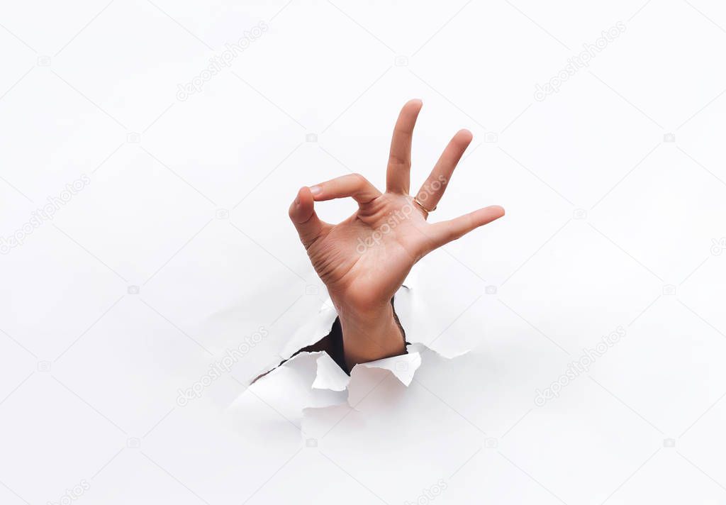 Hand ok sign. Hand coming out into hole. Copy space.