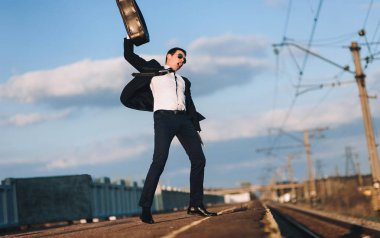 Bir bavul ile bir takım elbise genç İngiliz işadamı kariyerinde başarılar sevinler. İyi haberlerim var. Kayma, tatil konsepti.