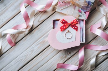 Evlilik teklifi kavramı. Bir hediye kutusu ahşap zemin üzerinde bir nikah yüzüğü. Üstten Görünüm.